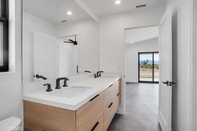 bathroom featuring concrete flooring, vaulted ceiling, vanity, and toilet