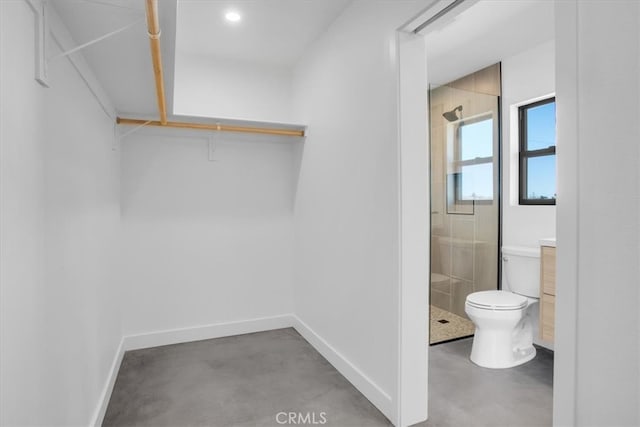 bathroom featuring walk in shower, vanity, toilet, and concrete floors