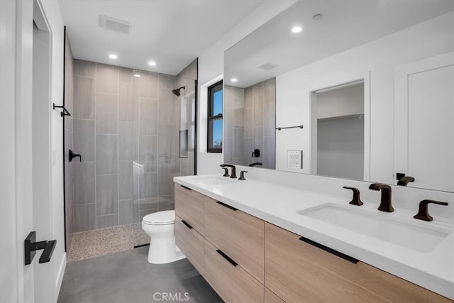 bathroom featuring tiled shower, vanity, and toilet