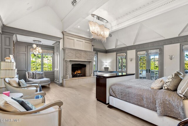 bedroom with an inviting chandelier, light hardwood / wood-style flooring, a premium fireplace, and multiple windows