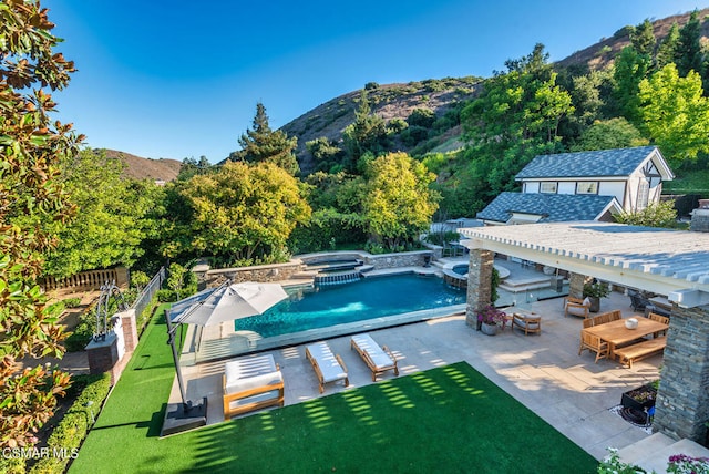 view of swimming pool featuring a patio, a mountain view, an in ground hot tub, and a yard