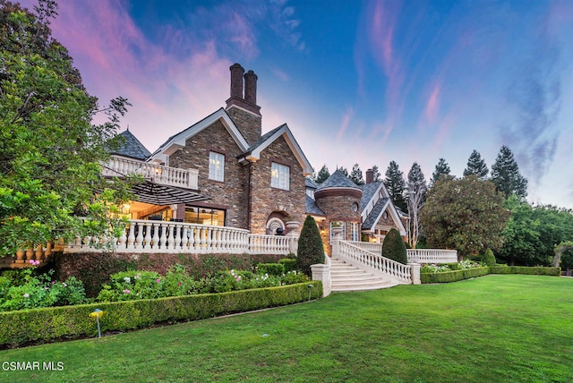 back house at dusk with a lawn and a wooden deck