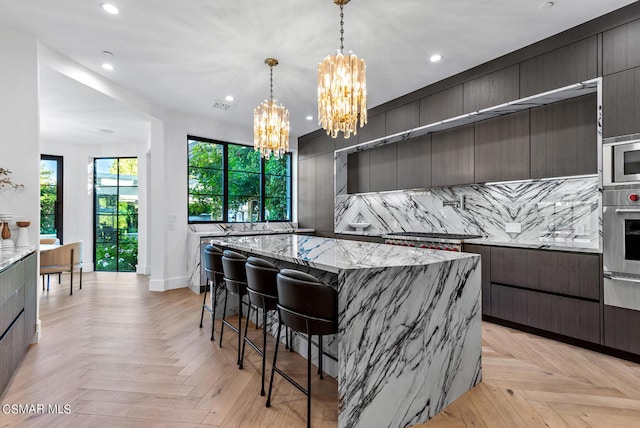 kitchen featuring a notable chandelier, hanging light fixtures, appliances with stainless steel finishes, light parquet floors, and a spacious island