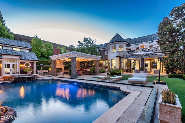 pool at dusk with a pergola, an in ground hot tub, and a patio area