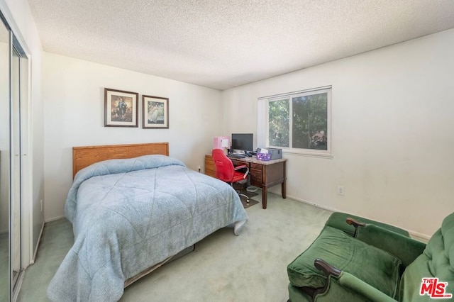 carpeted bedroom featuring a textured ceiling and a closet