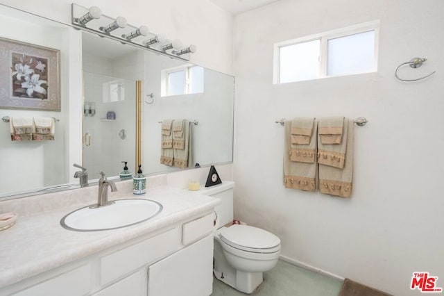 bathroom featuring vanity, toilet, plenty of natural light, and a shower with shower door