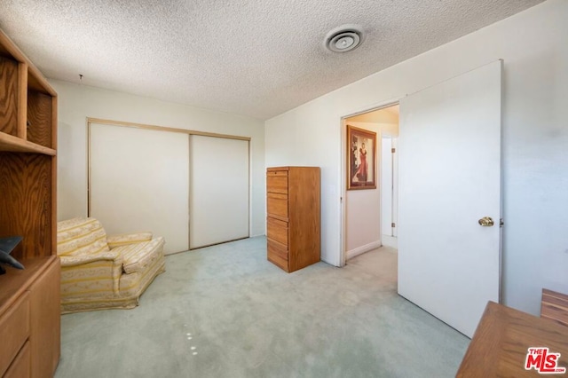 bedroom featuring a textured ceiling, light colored carpet, and a closet