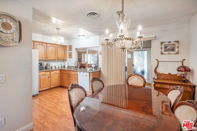 dining room with sink, light hardwood / wood-style floors, a healthy amount of sunlight, and a notable chandelier