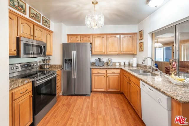 kitchen with appliances with stainless steel finishes, sink, decorative light fixtures, an inviting chandelier, and light hardwood / wood-style floors