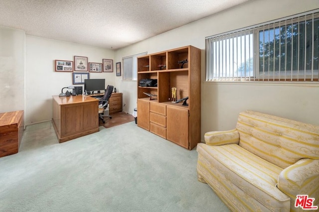 carpeted home office featuring a textured ceiling