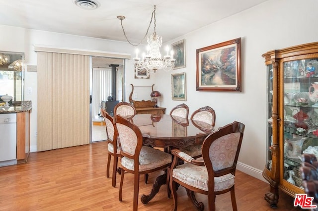 dining room featuring a chandelier, a wood stove, and light hardwood / wood-style flooring