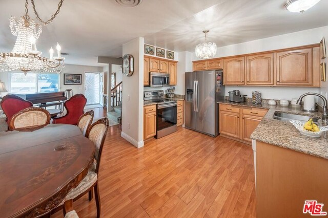 kitchen with sink, a chandelier, decorative light fixtures, appliances with stainless steel finishes, and light wood-type flooring