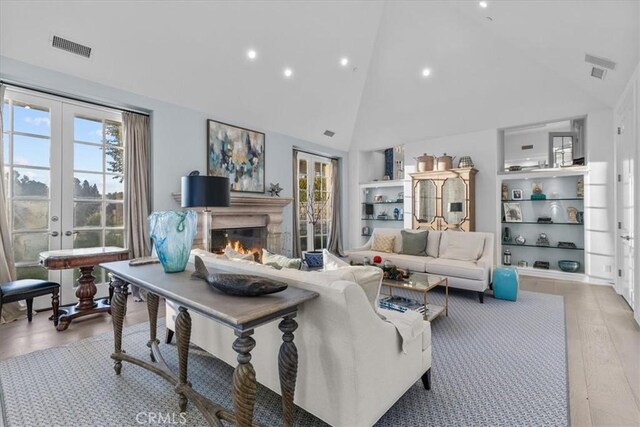 living room featuring light hardwood / wood-style floors, high vaulted ceiling, and french doors