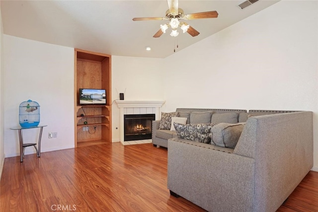 living room featuring vaulted ceiling, ceiling fan, hardwood / wood-style flooring, and a fireplace