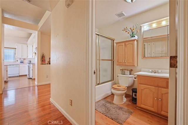 full bathroom featuring vanity, toilet, combined bath / shower with glass door, and hardwood / wood-style flooring