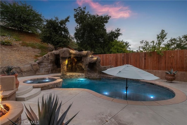 pool at dusk with a patio and an in ground hot tub