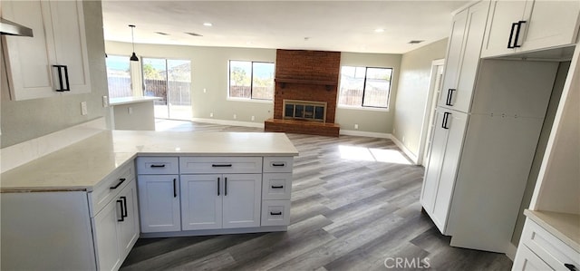 kitchen featuring a brick fireplace, white cabinets, and plenty of natural light