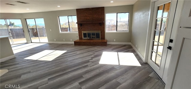 unfurnished living room with a fireplace, plenty of natural light, and dark hardwood / wood-style floors