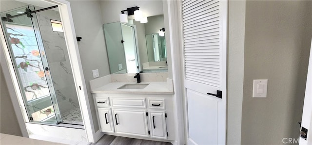 bathroom with walk in shower, vanity, and wood-type flooring