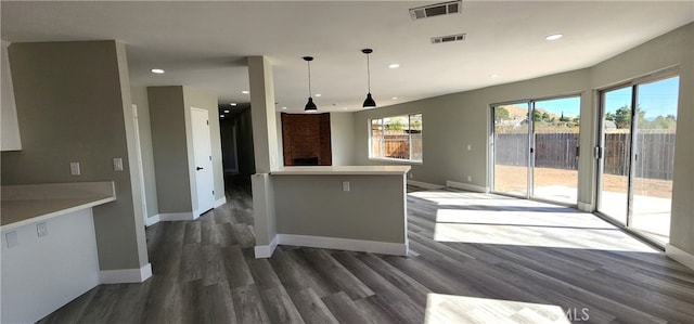 kitchen with a fireplace, hanging light fixtures, and dark hardwood / wood-style floors