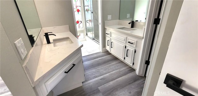 bathroom with two vanities, a sink, and wood finished floors