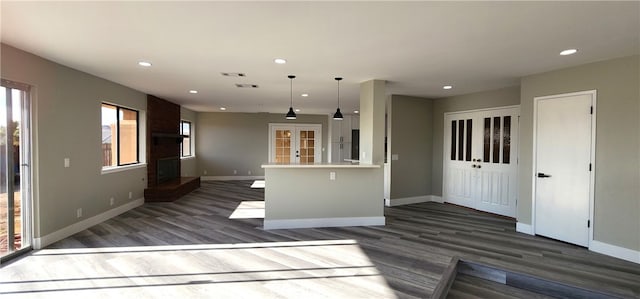 kitchen featuring a brick fireplace, hanging light fixtures, dark wood-type flooring, and kitchen peninsula