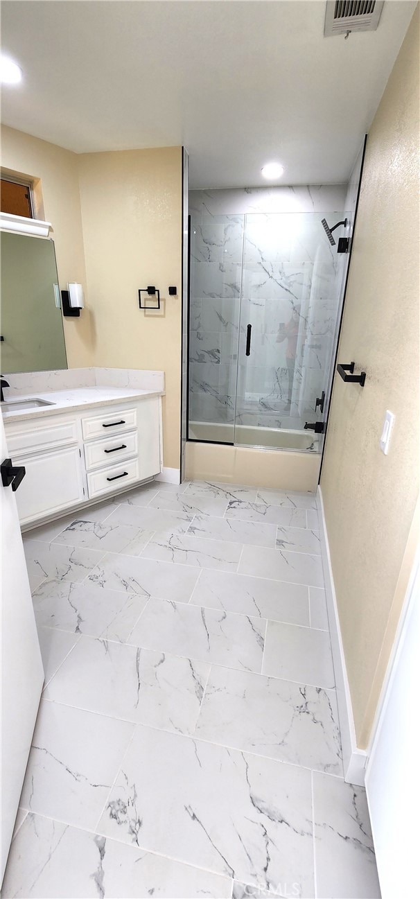 bathroom featuring a shower with shower door and vanity