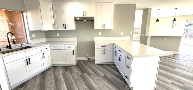 kitchen with pendant lighting, kitchen peninsula, white cabinets, and sink