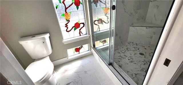 bathroom featuring toilet, marble finish floor, and a stall shower