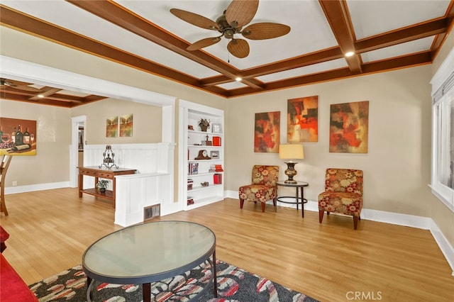 sitting room featuring beam ceiling, built in shelves, light wood-type flooring, and ceiling fan