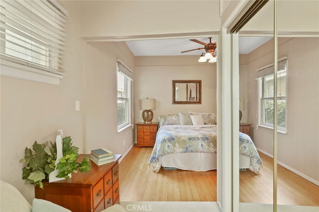 bedroom featuring light hardwood / wood-style floors, multiple windows, a closet, and ceiling fan