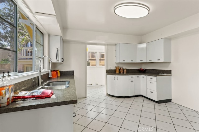 kitchen featuring sink, light tile patterned floors, a wealth of natural light, and white cabinets