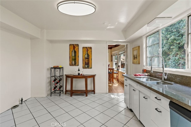 kitchen with white cabinetry, light tile patterned floors, sink, and dishwasher