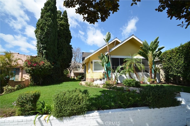 view of front of home with a front yard and a sunroom