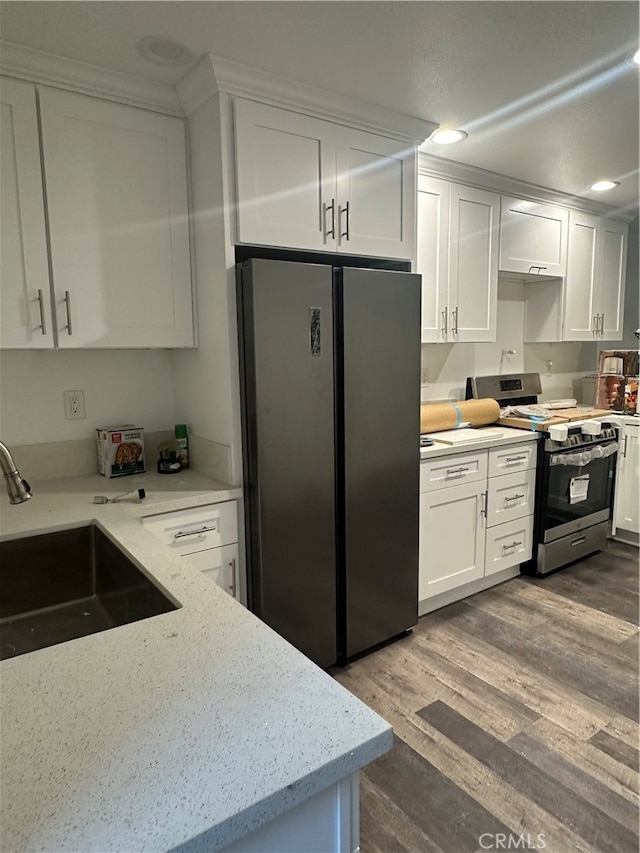 kitchen featuring light wood-type flooring, sink, white cabinetry, stainless steel appliances, and light stone countertops