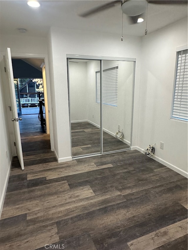 unfurnished bedroom featuring dark hardwood / wood-style floors, ceiling fan, and a closet