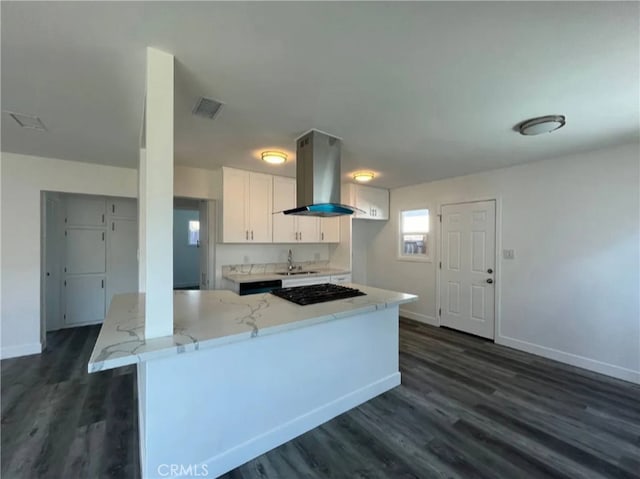 kitchen with white cabinetry, island range hood, light stone countertops, black gas cooktop, and dark hardwood / wood-style floors