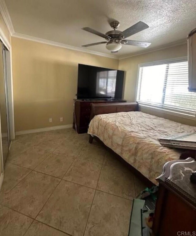 bedroom featuring ceiling fan, tile patterned flooring, crown molding, and a textured ceiling