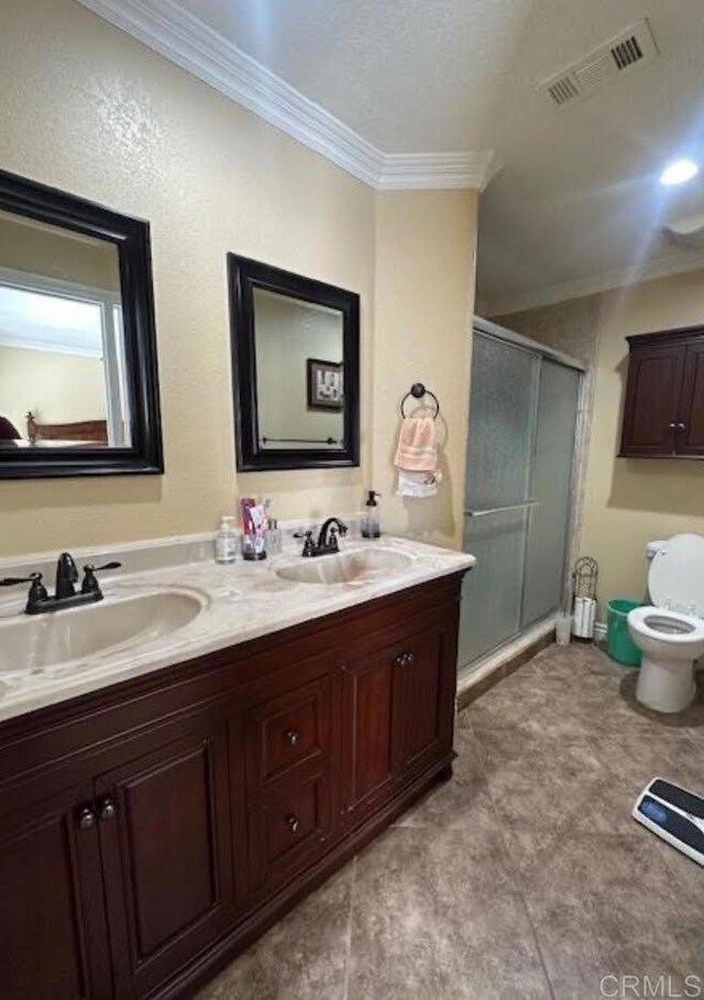 bathroom with crown molding, a shower with door, vanity, and toilet