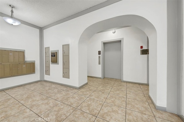 unfurnished room with a textured ceiling, lofted ceiling, light tile patterned floors, and a mail area