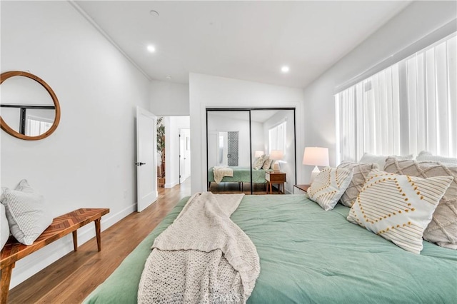 bedroom with a closet, hardwood / wood-style floors, and vaulted ceiling