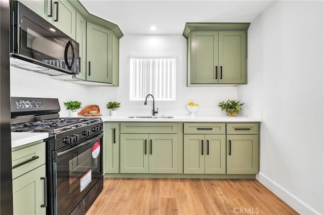 kitchen with black appliances, green cabinets, sink, and light hardwood / wood-style flooring