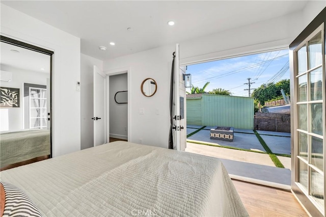 bedroom featuring access to exterior, light wood-type flooring, and a wall mounted AC