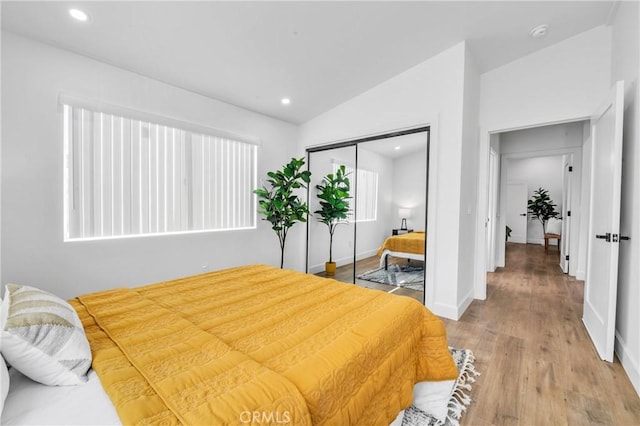 bedroom with hardwood / wood-style flooring, a closet, and lofted ceiling