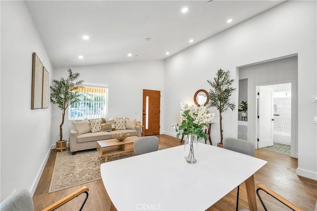 dining area featuring hardwood / wood-style floors and high vaulted ceiling