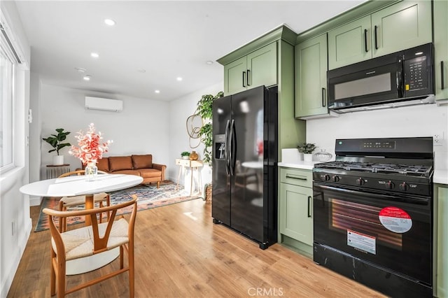 kitchen with black appliances, green cabinets, light wood-type flooring, and a wall mounted AC