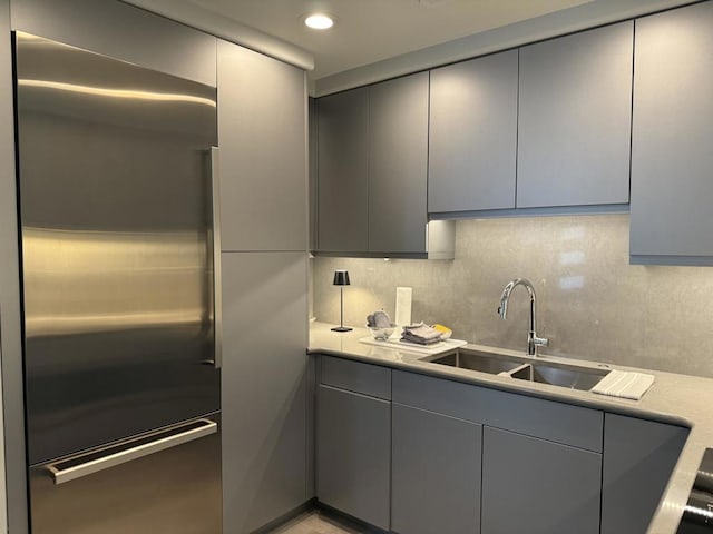 kitchen with sink, stainless steel built in refrigerator, decorative backsplash, and gray cabinets