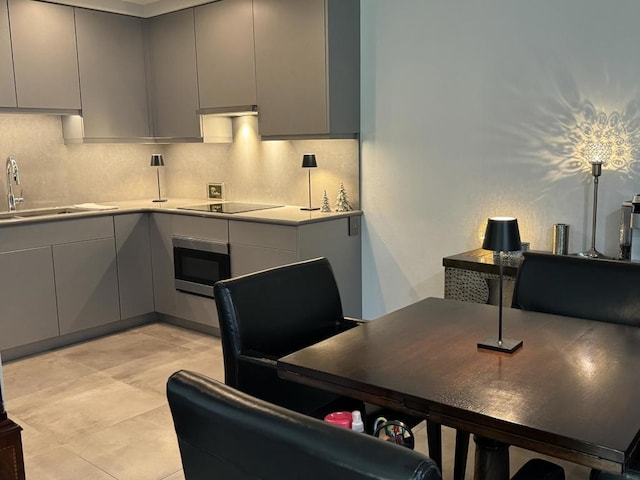 kitchen featuring sink, black electric stovetop, gray cabinets, and oven