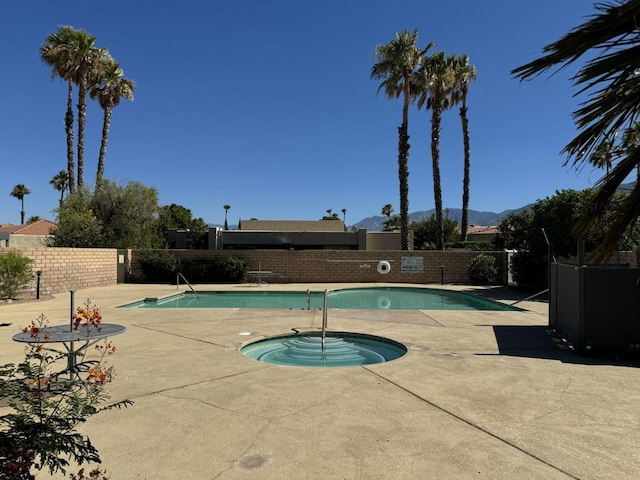 view of swimming pool featuring a mountain view, a hot tub, and a patio