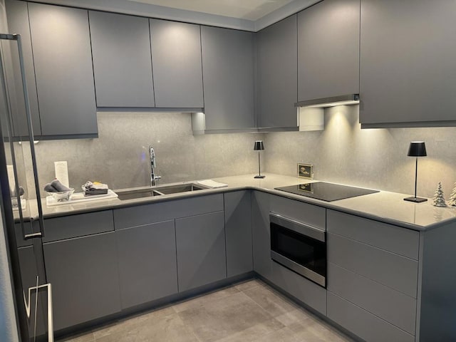 kitchen featuring oven, gray cabinets, black electric cooktop, and sink